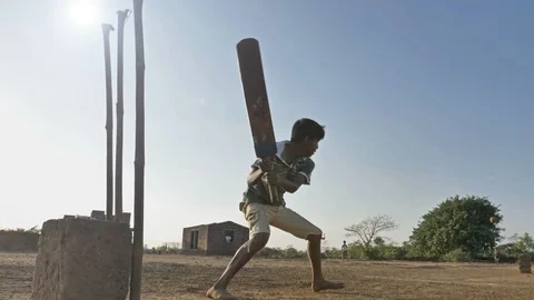 Slow motion shot of a young kid hits the ball and runs in village. Stock Footage 89081214