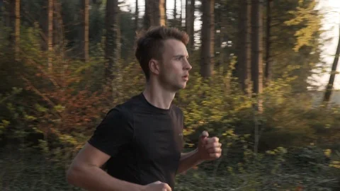 Slow motion shot of young man athlete running through forest, slow motion Stock Footage 129614414