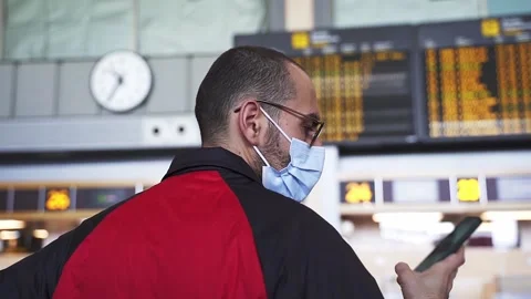 Slow motion shot of young man by airport panel looking at smartphone Stock Footage 169937186