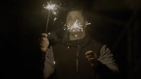 – Slow motion shot of young man having fun with sparkler outside. Stock Footage 300205022