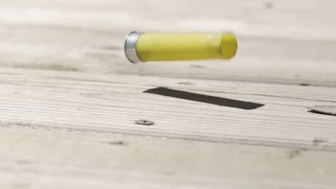 Slow motion shotgun shell hits ground and rolls offscreen 库存影片 79470081