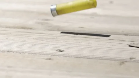 Slow motion shotgun shell hits ground and rolls 库存影片 79470086