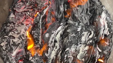 Slow motion shows embers and ashes smoldering in trash can Stock Footage 266147296