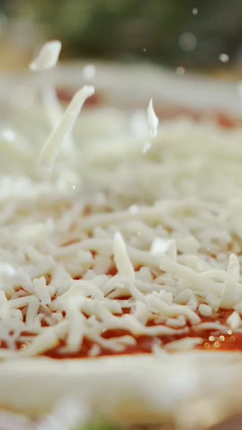 Slow motion shredded mozzarella cheese falling on tomato sauce pizza dough .. Stock Footage 337519199