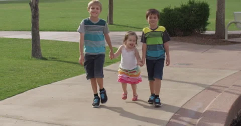 Slow Motion Siblings Walking on the Sidewalk and Smiling Together Stock Footage 61652058