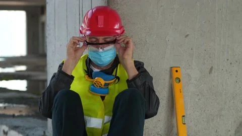 Slow Motion Sick worker in medical face mask sits at construction site Stock Footage 147279761