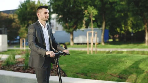 Slow-motion side-view of caucasian businessman riding on electric scooter along Stock Footage 194601877