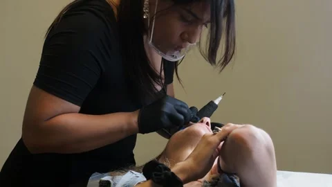 Slow motion side view of esthetician performing microblading with tool on Stock Footage 307480527