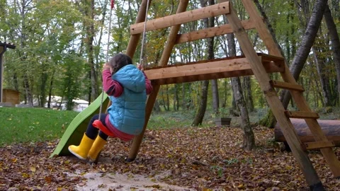 Slow Motion Side View of Little Girl Swinging in Autumn Playground Stock Footage 293853095