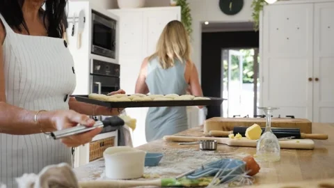 Slow motion side view of mother baking scones with daughter and brushing scones Stock Footage 130659469
