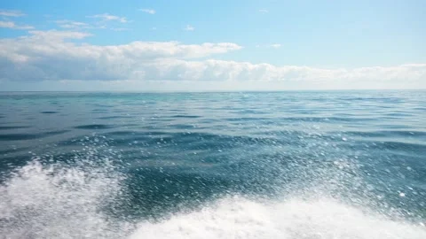 Slow motion side view from the motorboat through the spray onto the smooth blue Stock Footage 235722059