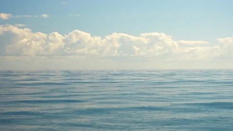 Slow motion side view of the smooth blue water surface. Clear sky and clouds on Stock Footage 235721985