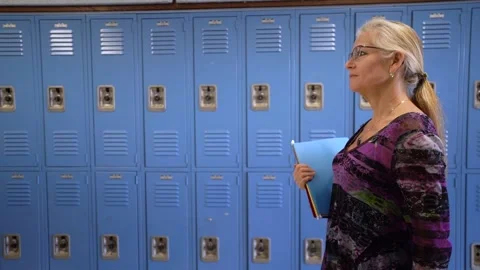 Slow motion side view of teacher walking down a hallway in an empty school Stock Footage 138961501