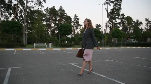 Slow motion side view of a young blonde woman walking across an empty parking Vídeos de archivo 333070914