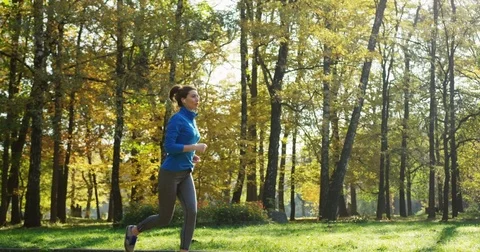 Slow motion from the side of young sporty woman in headphones jogging in the Stock Footage 82503164