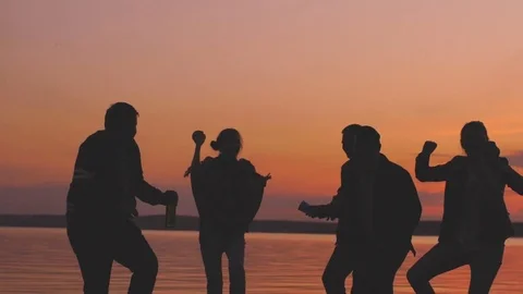 Slow motion of Silhouette group young dancing people have a party at beach on Stock Footage 76099352