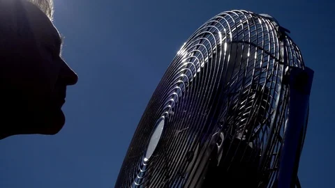 Slow motion: Silhouette of a man facing a powered fan to get cool. Vídeos de archivo 91378047