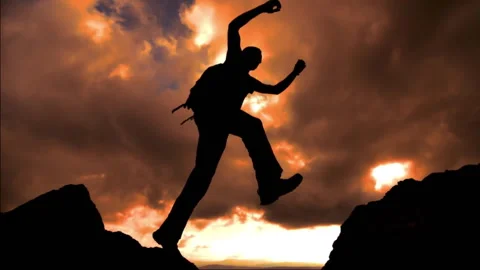 Slow motion  silhouette of a trail runner jumping on a rock top Stock Footage 266997096