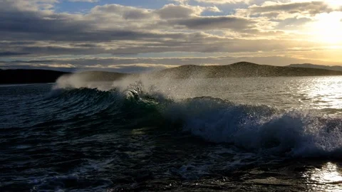 Slow motion of silhouetted wave breaking on rocky shore with offshore winds a Vidéo 107877217