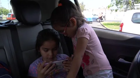 Slow motion of sisters looking at the cell phone inside a car in the daytime 库存影片 150917419