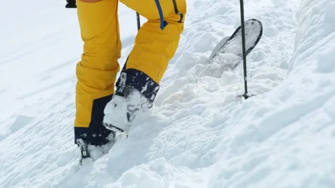 Slow motion of skier trying to shake off snow from their skis during sunny day Stock Footage 129127064