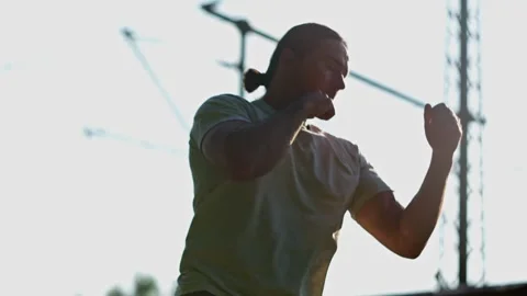 Slow motion. A skilled fighter practices dynamic punches against a vivid sunset Stock Footage 316540010