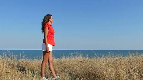 Slow motion. Slender Woman in red stand against sea. Focus change Stock Footage