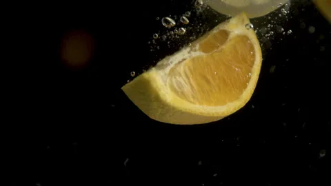 Slow Motion of a Slice of Lemon Falling Into a Pool of Water with a Black Stock Footage 270408677