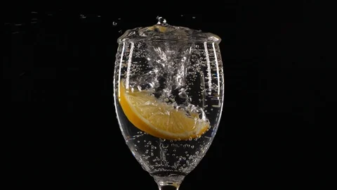 Slow motion of slice of lemon fruit falling down in a water glass with soda Stock Footage 123510769
