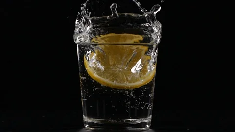 Slow motion of slice of lemon fruit falling down in a water glass with soda  Stock Footage 123510812