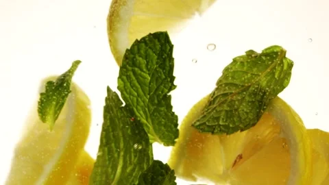 Slow motion slices of lemon or orange fruit and mint leaves splashing in water Stock Footage 267352471