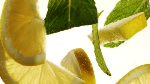 Slow motion slices of lemon or orange fruit and mint leaves splashing in water Stock Footage 269622165