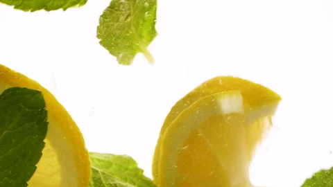 Slow motion slices of lemon or orange fruit and mint leaves splashing in water Stockbeeldmateriaal 306524438