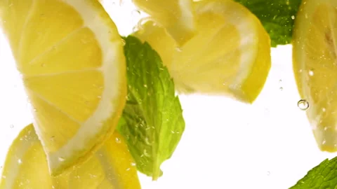 Slow motion slices of lemon or orange fruit and mint leaves splashing in water Stock-Footage 308906567