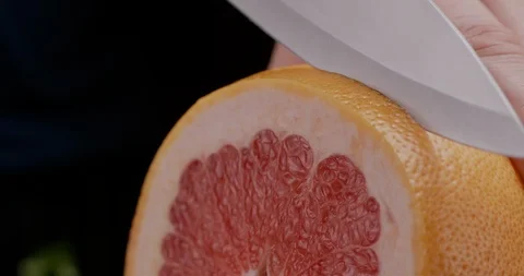 Slow motion of slicing grapefruit with sharp knife in the kitchen Stock Footage 125852059