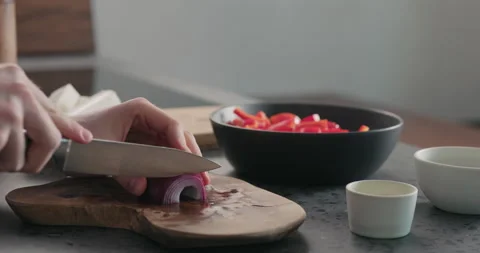 Slow motion slide shot of man slice red onion on olive wood board Video stock 134904096