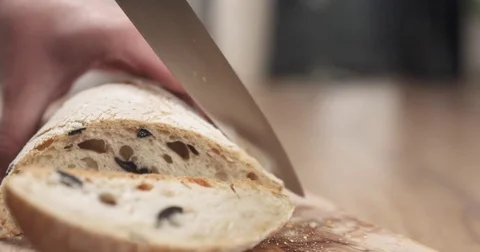 Slow motion slide shot of young female hands slicing ciabatta with olives on Stock Footage
