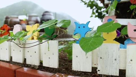 Slow Motion Slider Shot of Rainy Garden Fence with Colorful Wooden Decor Видео 342478624