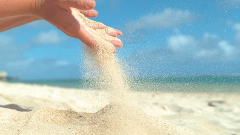 SLOW MOTION: Small grains of sand sift through unrecognizable woman's fingers. Stock Footage 90704426
