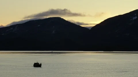 Slow motion of small motor boat floating on lake as sunsets behind mountains Stock Footage 129109165