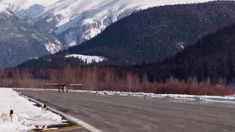 Slow Motion: Small Plane Taking Off Runway With Snow Capped Mountains Stock Footage 72875263