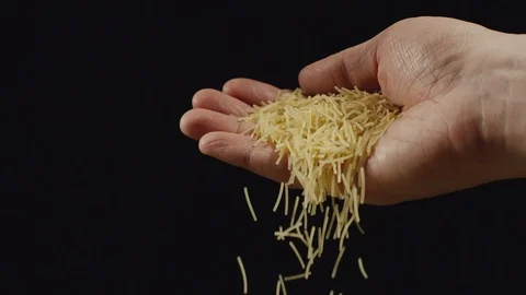 SLOW MOTION: Small vermicelli pasta falling from a hand on a black background Stock Footage 102212448