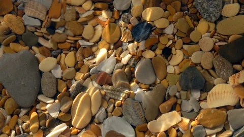 Slow motion of small waves on shallow pure water with pebble bottom close up. Stock Footage 98094875