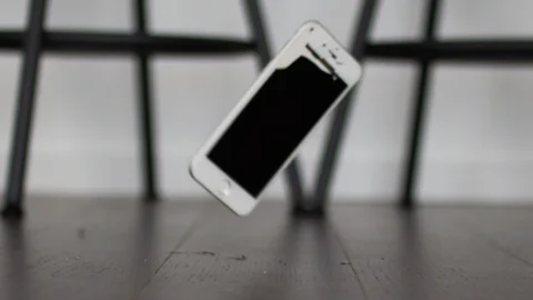 Slow motion smart phone landing on the ground and smashing Stock Footage