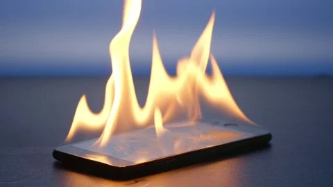 SLOW MOTION: Smartphone is burning on a table on a blue background Stock Footage 73412955