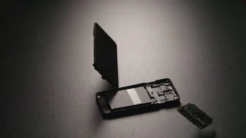 SLOW MOTION: Smartphone falls on a floor and breaks on a parts in center Stock Footage 72374573