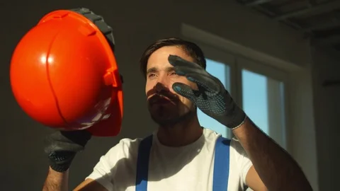 Slow motion, smiling builder stands and puts on protective helmet Stock Footage 124842359