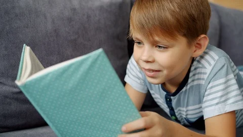 Slow motion of smiling child reading book alone enjoying fairy-tale feeling Stock Footage 123331646