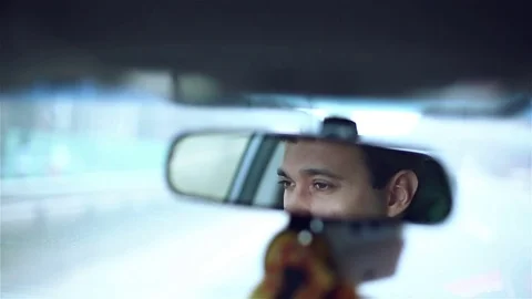 Slow motion. Smiling man in mirror while driving car in a city. Stock Footage 71027814