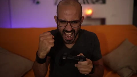 Slow Motion: smiling man plays a video game on the sofa having fun. Winner sign Stock Footage 136536857